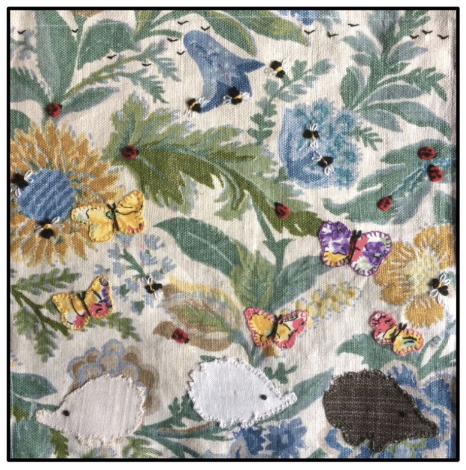 A textile panel with wildlife, hedgehogs, flowers, butterflies